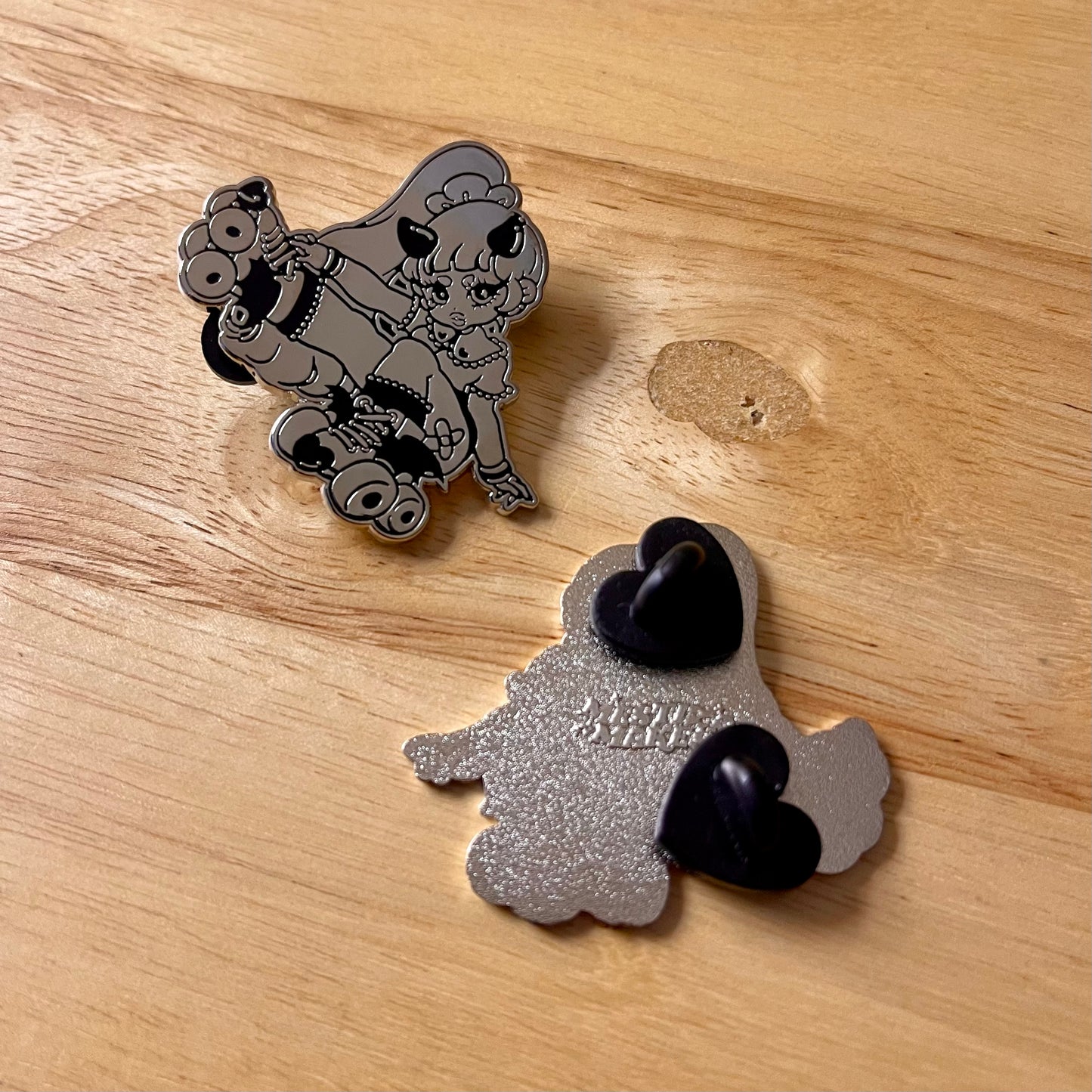 Two metallic pins on a wooden surface