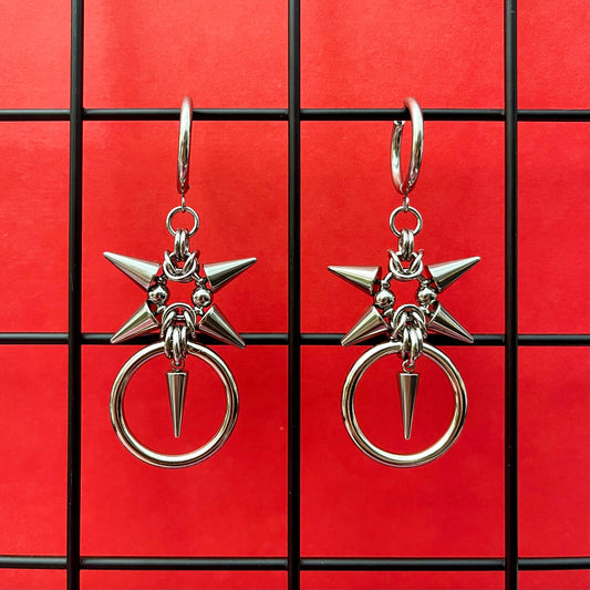 A pair of stainless steel spiky earrings with a heavy o-ring on a red background.