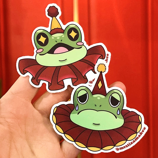 Two waterproof stickers featuring a cartoon frog dressed as a clown, one with a happy expression and one with a sad expression, held against a red curtain background.